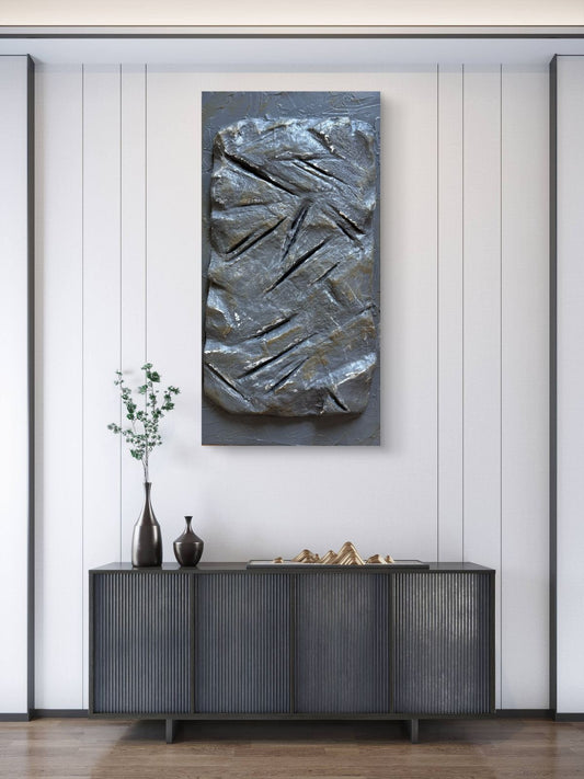 Modern sculptural textured artwork featuring a raw stone-inspired surface with carved linear details in earthy grey tones, designed as a bold contemporary statement piece for luxury interiors.